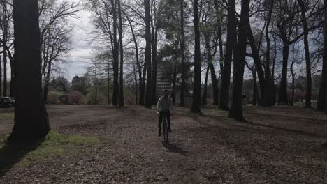 Man-biking-towards-the-camera-while-it-pushes-out,-high-fps,-in-the-woods