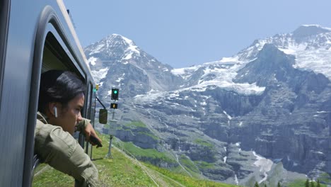 Paseo-Panorámico-En-Tren-En-El-Valle-De-La-Ventana-De-Montaña-De-Los-Alpes-Con-Un-Hombre-Mirando-Desde-La-Ventana,-Lauterbrunnen-Suiza