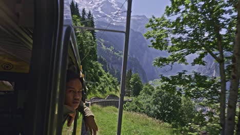 Paseo-Panorámico-En-Tren-En-El-Valle-De-La-Ventana-De-Montaña-De-Los-Alpes-Con-Un-Hombre-Mirando-Desde-La-Ventana,-Lauterbrunnen-Suiza-1