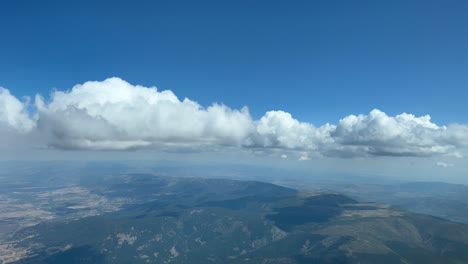 Unique-pilot-point-of-view-during-the-descent-for-the-approach-to-Madrid-airport,-with-some-tiny-cumulus-and-a-deep-blue-sky
