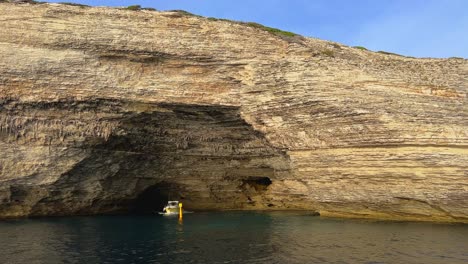 Tourist-boat-comes-out-of-Bonifacio-cliffs-St-Antoine-cave-in-Corsica,-France