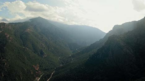 Flight-over-a-mountain-ridge-to-reveal-green-mountains-in-Corsica