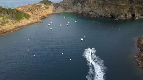 Aerial-tracking-shot-of-a-jet-ski-in-a-beautiful-cala-of-the-Costa-Brava,-Catalonia