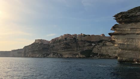 Moving-foward-toward-Bonifacio-Corse-city-perched-on-high-cliff-as-seen-from-navigating-sailboat-in-Mediterran-sea,-Corsica-in-France