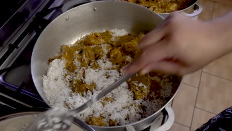 Chef-Agregando-Arroz-Blanco-A-La-Capa-De-Curry-De-Pollo-En-Una-Olla-Grande