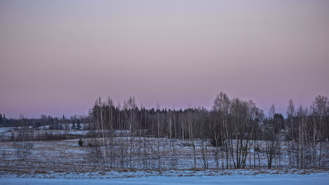 Static-shot-of-moon-sets-just-as-the-sun-rising-in-the-background-at-dawn-in-timelapse-over-rural-landscape
