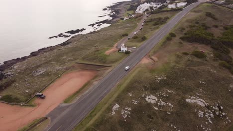 Aerial-tracking-shot-of-white-car-on-mountain-road-in-punta-ballena,uruguay