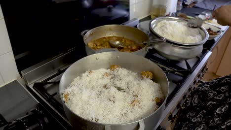 Weißer-Reis-Wird-Auf-Hühnercurry-In-Einem-Großen-Topf-In-Der-Küche-Hinzugefügt