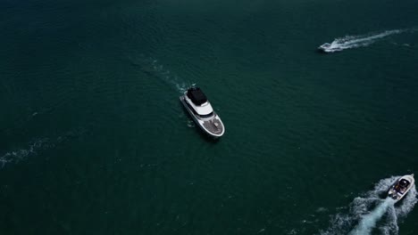 Eine-Luxusyacht,-Die-Sich-Langsam-Zwischen-Kleineren-Booten-Auf-Einem-Fluss-Bewegt,-Aus-Der-Luftdrohnenperspektive,-Die-Auf-Das-Wasser-Darunter-Blickt
