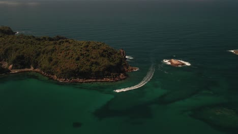 Cinematic-drone-footage-of-speed-boat-racing-around-small-secluded-island