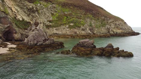 Slider-Shot-Of-Rocks-Pile-Middle-Formed-In-Water-Sea,-Porth-Wen-Beach,-United-Kingdom