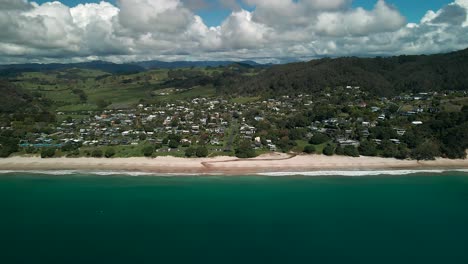 Flying-down-small-beach-holiday-town-in-New-Zealand---Hahei