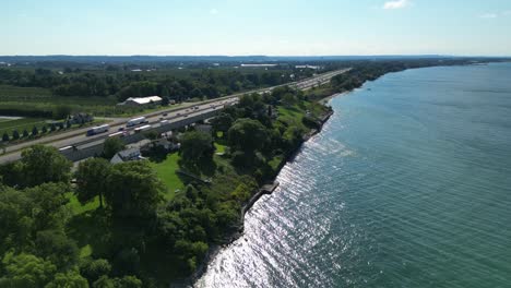 Reveal-shot-of-highway-in-Lincoln-along-lake,-aerial