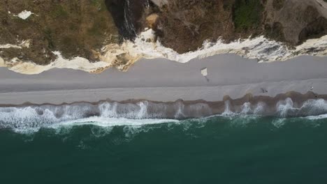 The-famous-cliffs-of-etretat-in-normandy-in-france,-filmed-with-the-drone-from-above,-right-on-the-beach-with-waves