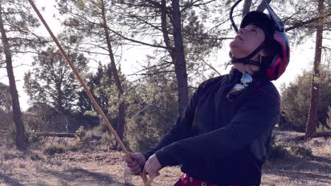 Woman-shakes-rope-attached-to-a-tree-while-pruning-trees-in-a-pine-forest-in-Spain