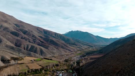 Drone-flyover-Vineyard-cultivation-in-Limarí-Valley,-surrounded-by-rugged-mountains