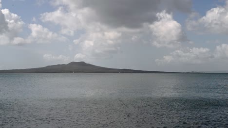 Dormant-Rangitoto-volcano-between-a-beautiful-cloudscape-and-the-turquoise-pacific-ocean-with-the-tide-pulling-out
