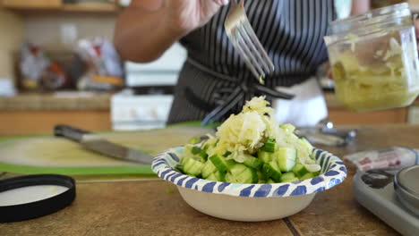 Mixing-sauerkraut-with-the-cucumbers-and-other-ingredients-for-a-chopped-salad---ANTIPASTO-SALAD-SERIES