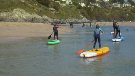 Children-paddleboard-on-a-Cornish-beach-in-gentle-water
