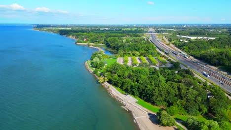 Aerial-over-Lake-Ontario-and-Charles-Daley-Park-next-to-QEW-highway,-Ontario