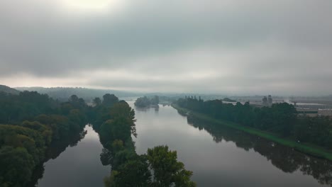 Aerial-shot-of-morning-foggy-atmosphere-over-a-wide-river