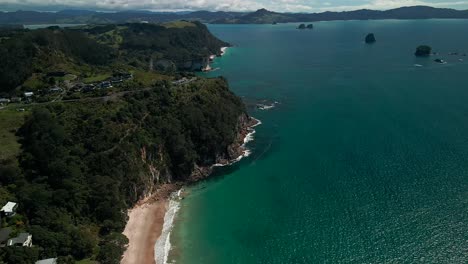 Flying-backwards-across-Hahei-beach,-New-Zealand
