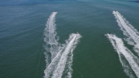 Aerial-View-Of-Jet-Skiers-Racing-In-The-Sea-To-The-Letitia-Beach-In-Fingal-Head,-NSW,-Australia