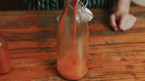 Pouring-creamy-red-pepper-sauce-in-a-glass-bottle-for-storage