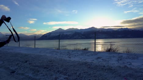 Silueta-De-Una-Mujer-Tomando-Una-Foto-De-Invierno-De-Una-Montaña-En-Alaska-A-Lo-Largo-Del-Río
