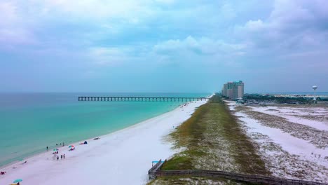Drone-aerial-view-flying-down-the-white-sand-beach-of-Navarre-Florida-towards-the-Pier-and-the-boardwalk