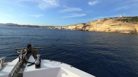 Ansicht-Des-Segelbootbugs,-Der-In-Richtung-Der-Felsen-Der-Insel-Korsika-Und-Des-Leuchtturms-Capo-Pertusato-In-Frankreich-Navigiert,-50fps