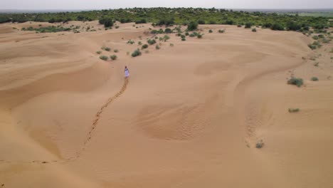 Aerial-View-Of-Women-In-White-Dress-Walking-Across-Desert-Landscape