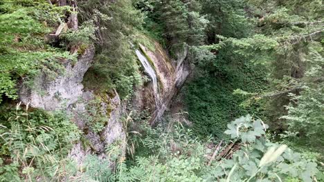 Kleiner-Schöner-Wasserfall-In-Den-Bergen,-Umgeben-Von-Felsen-Und-Grünen-Bäumen