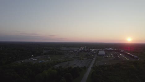 From-a-great-height,-a-drone-captured-the-sun-setting-in-the-horizon-and-a-small-town-in-Ohio-surrounded-by-trees