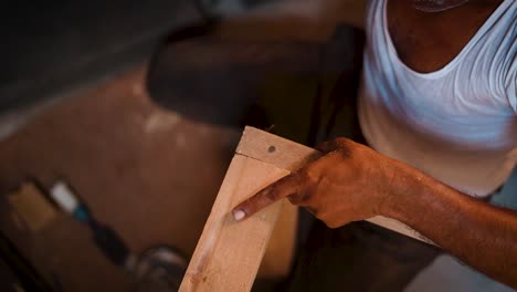 Closeup-of-a-carpenter-working-in-his-workshop,-carpenter-hammering-nails-in-a-piece-of-wood,-carpenter-making-furniture-parts