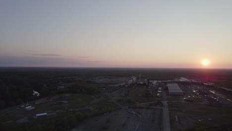 Drohne-Erfasst-Eine-Stadt,-Umgeben-Von-Bäumen-Und-Dem-Sonnenuntergang-Am-Horizont