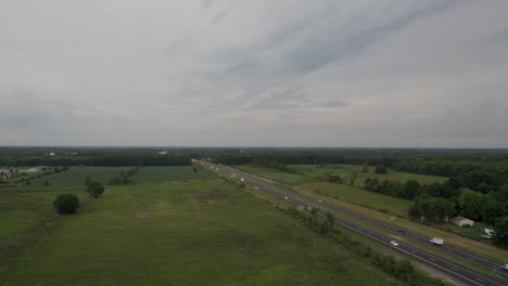 An-aerial-view-over-a-meadow-by-a-straight-road-with-an-open-field-on-the-other-side
