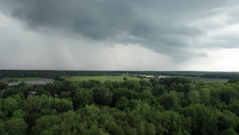Drone-capture-the-dense-tree-covered-forest-and-green-landscape-with-dark-gray-cloud-hovering-in-the-distance