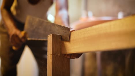 Closeup-of-a-carpenter-cutting-a-piece-of-wood-with-crosscut-saw,-carpenter-using-a-crosscut-saw,-carpenter-working-in-his-workshop-making-furniture