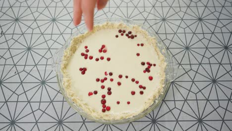 Man-placing-berries-on-top-of-a-lingonberry-pie