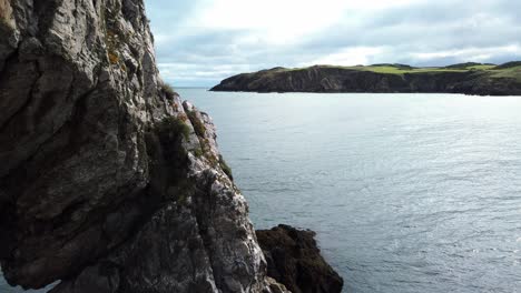Panning-across-Traeth-Porth-Wen-Beach-to-rugged-stone-archway-formation-on-the-Irish-sea-coast