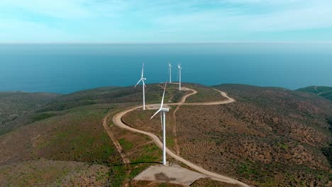 Dolly-in-aerial-view-of-a-vertical-line-of-wind-turbines-with-the-sea-in-the-background,-northern-Chile