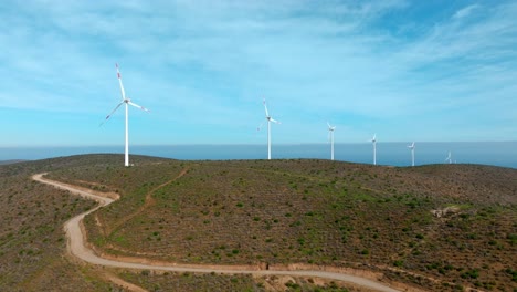 Aerial-boom-up-view-of-a-string-of-wind-turbines-on-a-sunny-day-in-the-arid-mountains-of-northern-Chile
