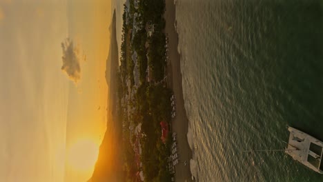 Aerial-approaching-shot-of-anchored-Catamaran-at-bay-of-Playa-Dorada-City-during-golden-sunset---vertical-shot