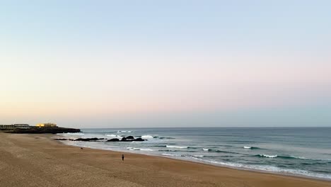 Drone-shot-of-Praia-do-Guincho-at-sunrise-in-Cascais,-overlooking-bar-do-guincho,-Muchaxo