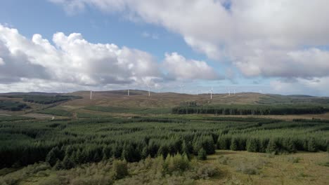 Aerial-drone-footage-of-fast-spinning-wind-turbines-in-a-Scottish-windfarm-surrounded-by-forestry-plantations-of-commercial-conifers-on-the-Kintyre-Peninsula,-Argyll,-Scotland
