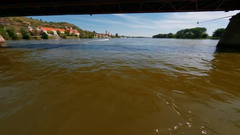 FPV-Tracking-Shot-Of-Speedboat-Passing-Under-Mautern-Bridge-In-Danube-River,-Austria