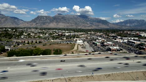Highway-traffic-on-I-15-at-daytime-near-Lehi-looking-towards-the-Wasatch-Front-and-American-Fork,-Utah---aerial-time-lapse