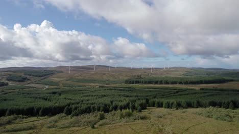 Aerial-drone-footage-flying-towards-wind-turbines-in-a-Scottish-windfarm-surrounded-by-forestry-plantations-of-commercial-conifers-on-the-Kintyre-Peninsula,-Argyll,-Scotland