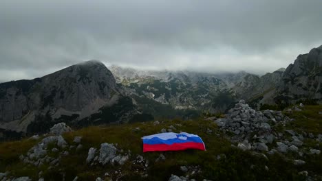 Footage-of-a-Slovenian-flag-set-on-top-of-mountains-in-the-Alps-filmed-with-a-drone-in-4k-with-forwarding-movement-with-cloudy-weather-and-mist-all-over-the-place
